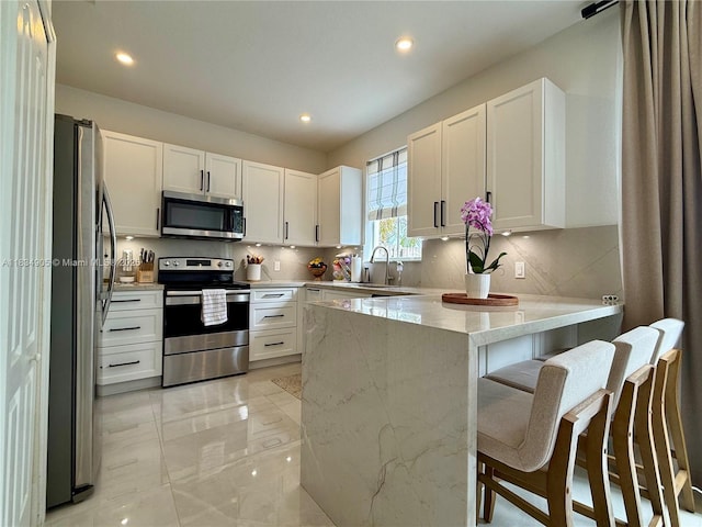 14902 SW 23rd Way, Miami, FL 33185 - kitchen featuring appliances with stainless steel finishes, a peninsula, decorative backsplash, white cabinets, and recessed lighting