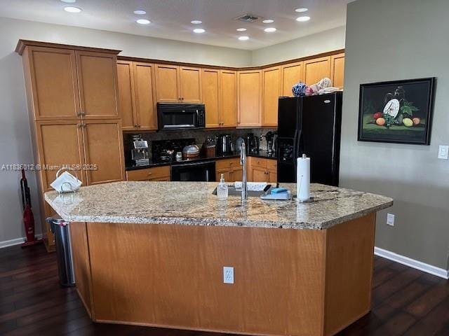 15562 SW 54th Ct, Miramar, FL 33027 - kitchen with black appliances, dark wood-type flooring, light stone countertops, a kitchen island with sink, and recessed lighting