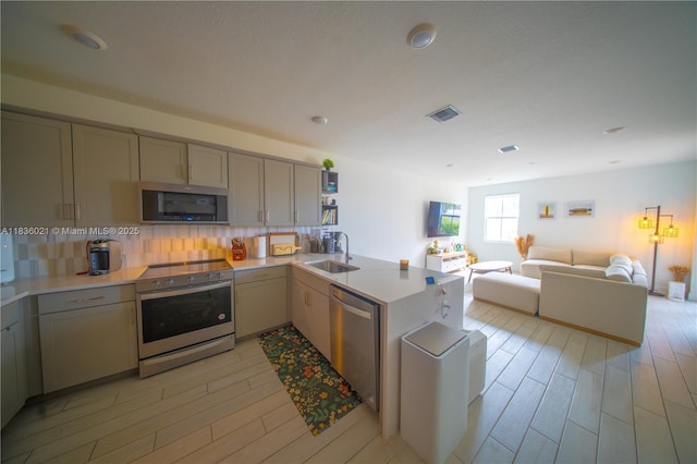 138 SW 171st Way, Pembroke Pines, FL 33027 - kitchen featuring stainless steel appliances, light wood finished floors, a peninsula, tasteful backsplash, and light countertops