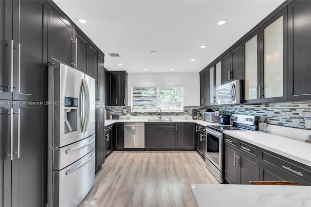 11433 NE 6th Ave, Biscayne Park, FL 33161 - kitchen featuring stainless steel appliances, light wood-style floors, decorative backsplash, light countertops, and recessed lighting