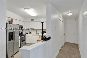 3400 NE 192nd St Unit 1403, Aventura, FL 33180 - kitchen with appliances with stainless steel finishes, a peninsula, and light countertops