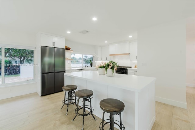 12241 SW 120th Ave, Miami, FL 33186 - kitchen with freestanding refrigerator, light wood-type flooring, a kitchen bar, open shelves, and light countertops