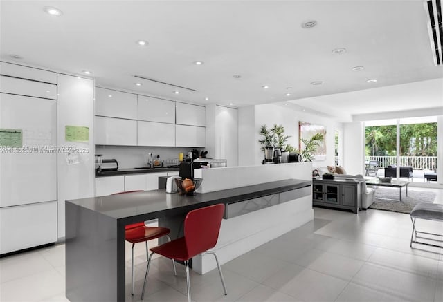 785 Crandon Blvd Unit 302, Key Biscayne, FL 33149 - kitchen featuring modern cabinets, dark countertops, white cabinets, a center island, and a breakfast bar area