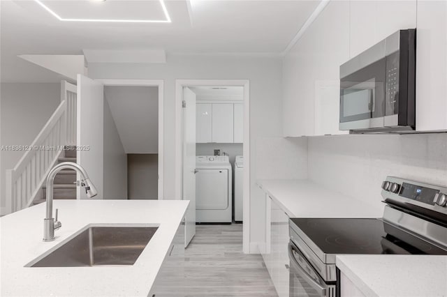 1170 SW 118th Ter, Davie, FL 33325 - kitchen featuring stainless steel appliances, washer and clothes dryer, modern cabinets, white cabinetry, and light wood-type flooring
