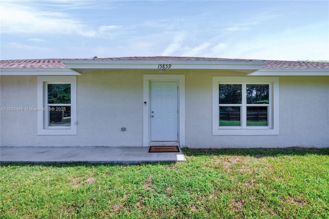 15859 N 68th Ct N, Loxahatchee, FL 33470 - property entrance featuring a yard, stucco siding, and a shingled roof