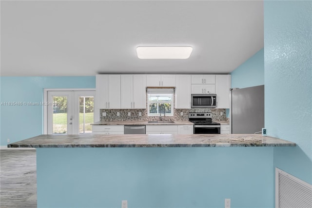 15859 N 68th Ct N, Loxahatchee, FL 33470 - kitchen featuring appliances with stainless steel finishes, tasteful backsplash, white cabinets, and french doors