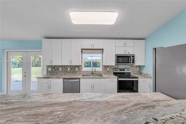 15859 N 68th Ct N, Loxahatchee, FL 33470 - kitchen with appliances with stainless steel finishes, decorative backsplash, white cabinets, french doors, and light stone countertops