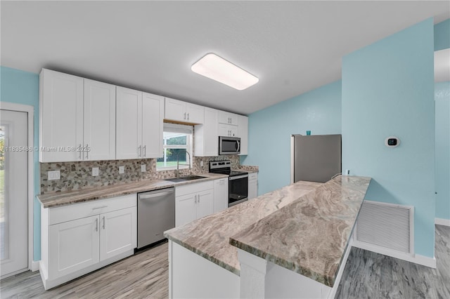 15859 N 68th Ct N, Loxahatchee, FL 33470 - kitchen featuring appliances with stainless steel finishes, vaulted ceiling, tasteful backsplash, light wood finished floors, and white cabinetry