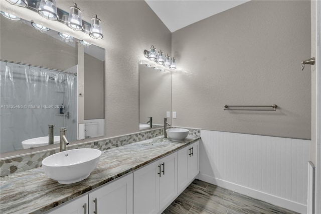 15859 N 68th Ct N, Loxahatchee, FL 33470 - bathroom with double vanity, a shower with curtain, wood finished floors, lofted ceiling, and wainscoting