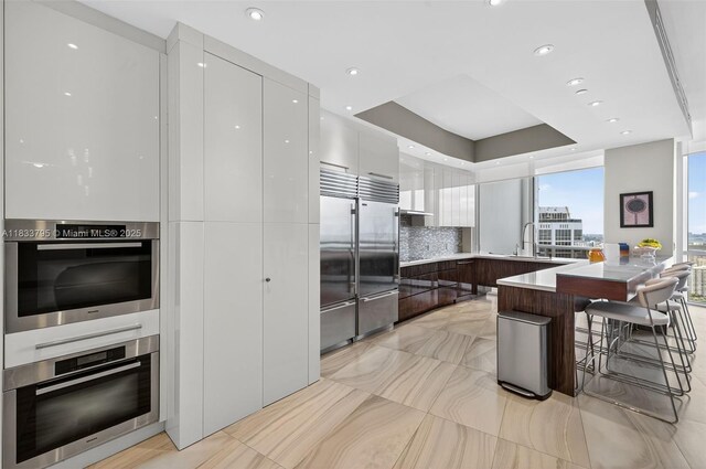 18201 Collins Ave Unit Ts2 & Ts3, Sunny Isles Beach, FL 33160 - kitchen featuring modern cabinets, a peninsula, stainless steel built in refrigerator, a breakfast bar, and tasteful backsplash