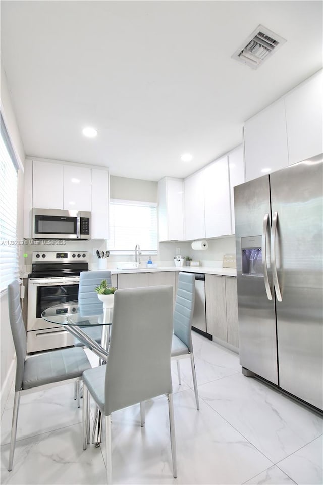 1226 NW 103rd St, Miami, FL 33147 - kitchen featuring stainless steel appliances, light marble finish flooring, modern cabinets, light countertops, and recessed lighting