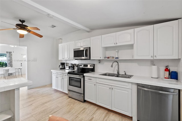 2946 SW 26th St, Miami, FL 33133 - kitchen with appliances with stainless steel finishes, tile countertops, open shelves, decorative backsplash, and white cabinets