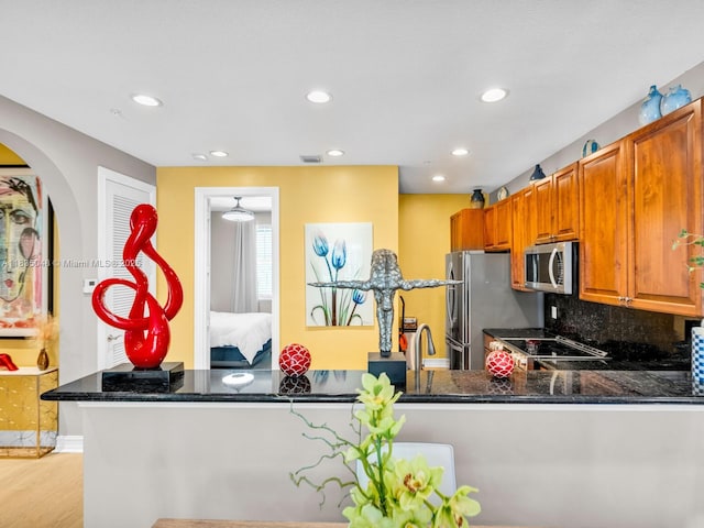 2249 NE 9th Ave, Wilton Manors, FL 33305 - kitchen featuring stainless steel microwave, recessed lighting, tasteful backsplash, arched walkways, and dark stone countertops