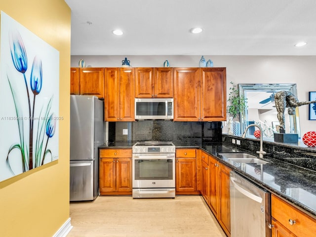 2249 NE 9th Ave, Wilton Manors, FL 33305 - kitchen with stainless steel appliances, brown cabinetry, light wood-type flooring, dark stone counters, and recessed lighting