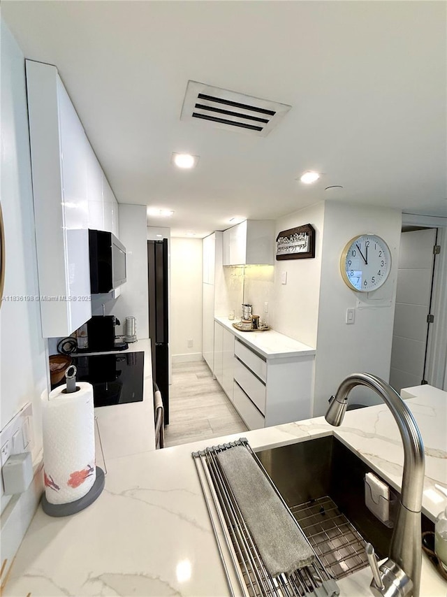 770 Claughton Island Dr Unit 1503, Miami, FL 33131 - kitchen with stainless steel microwave, white cabinetry, light stone countertops, recessed lighting, and modern cabinets