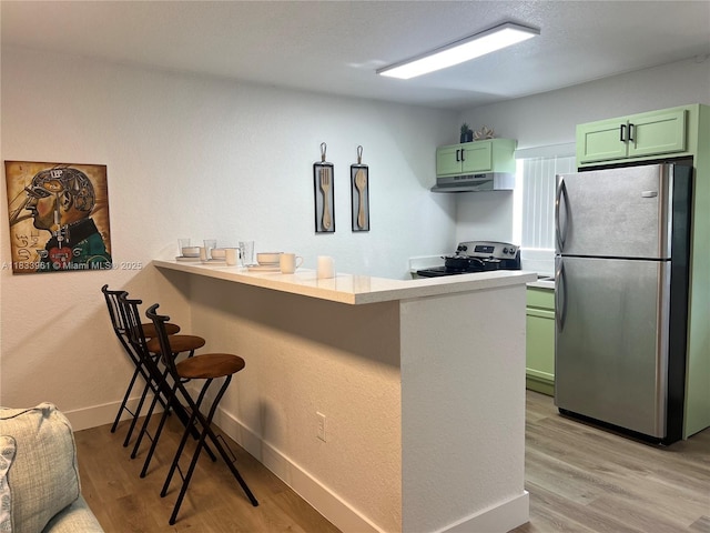 8921 NW 17th Ave, Miami, FL 33147 - kitchen featuring stainless steel appliances, green cabinetry, a breakfast bar, under cabinet range hood, and a peninsula