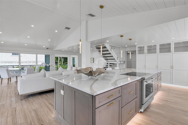 126 Villa Bella Dr, Islamorada, FL 33036 - kitchen featuring stainless steel electric stove, open floor plan, light wood finished floors, a large island, and white cabinetry