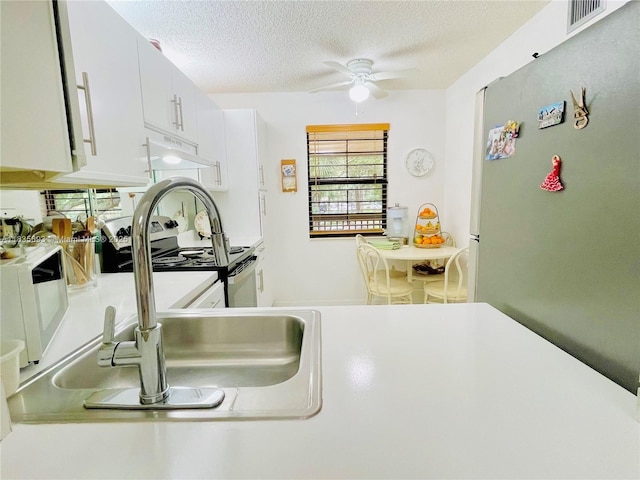 3137 S Carambola Cir S Unit 2369, Coconut Creek, FL 33066 - kitchen featuring freestanding refrigerator, ceiling fan, under cabinet range hood, white microwave, and a textured ceiling