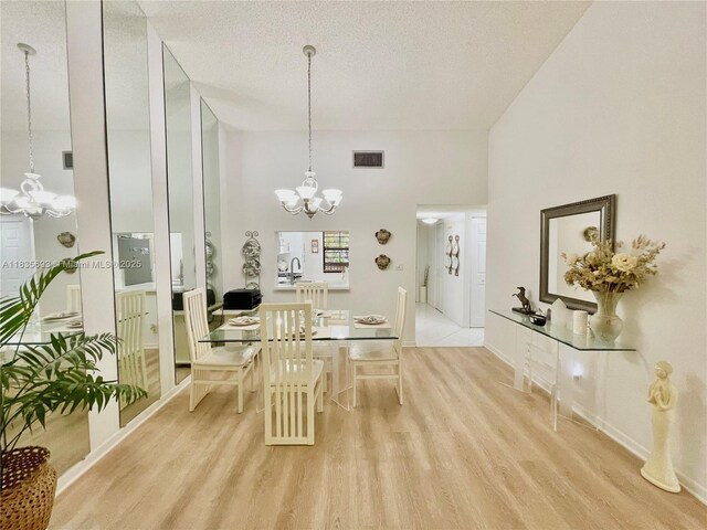 3137 S Carambola Cir S Unit 2369, Coconut Creek, FL 33066 - dining room with a chandelier, light wood finished floors, a towering ceiling, and a textured ceiling