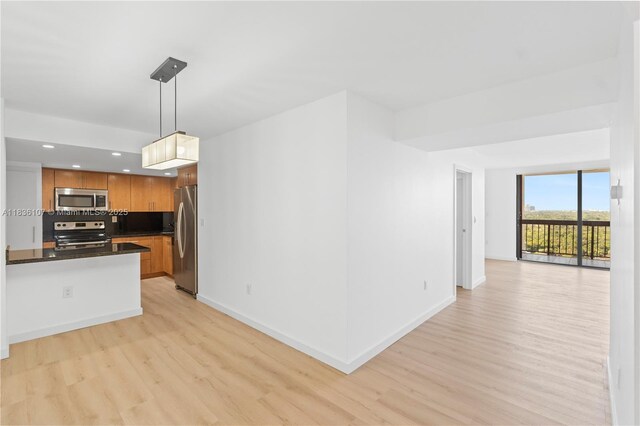 2333 Brickell Ave Unit 1908, Miami, FL 33129 - kitchen with stainless steel appliances, light wood-style flooring, dark countertops, open floor plan, and brown cabinetry