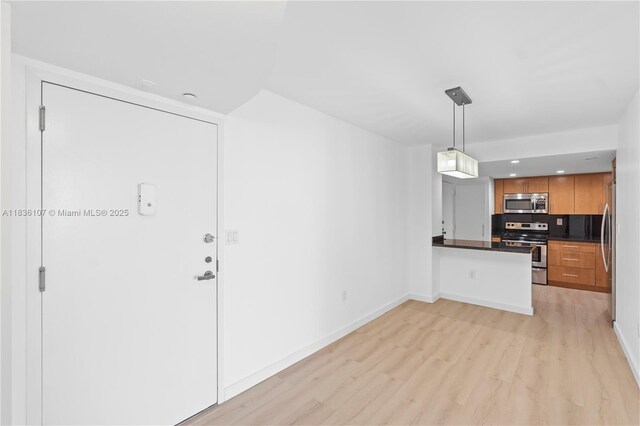 2333 Brickell Ave Unit 1908, Miami, FL 33129 - kitchen featuring appliances with stainless steel finishes, light wood finished floors, dark countertops, brown cabinetry, and a peninsula
