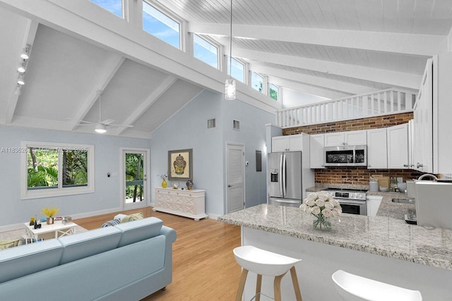 81975 Old Hwy, Islamorada, FL 33036 - kitchen featuring appliances with stainless steel finishes, a peninsula, open floor plan, high vaulted ceiling, and white cabinetry