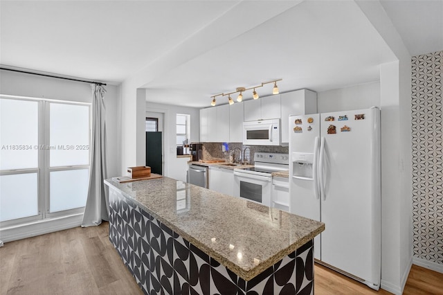 1340 Lincoln Rd Unit 403, Miami Beach, FL 33139 - kitchen featuring white appliances, white cabinets, light wood-style floors, decorative backsplash, and a center island