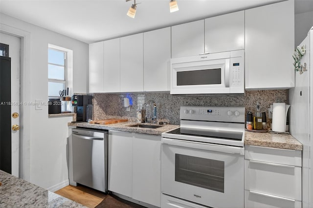 1340 Lincoln Rd Unit 403, Miami Beach, FL 33139 - kitchen featuring white appliances, decorative backsplash, white cabinets, and light wood finished floors