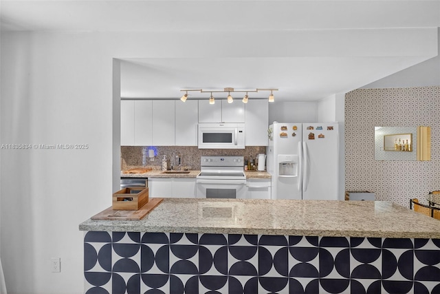 1340 Lincoln Rd Unit 403, Miami Beach, FL 33139 - kitchen with white appliances, a breakfast bar, white cabinets, and backsplash