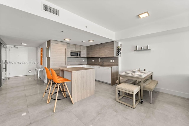 400 Sunny Isles Blvd Unit 616, Sunny Isles Beach, FL 33160 - kitchen with stainless steel microwave, butcher block countertops, a kitchen breakfast bar, and modern cabinets