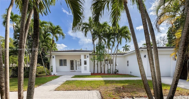 380 Morningside Dr, Miami Springs, FL 33166 - view of front of house with stucco siding, a front lawn, an attached garage, and driveway