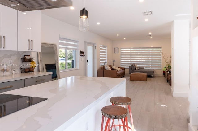 380 Morningside Dr, Miami Springs, FL 33166 - kitchen with black electric stovetop, hanging light fixtures, white cabinets, light stone counters, and recessed lighting