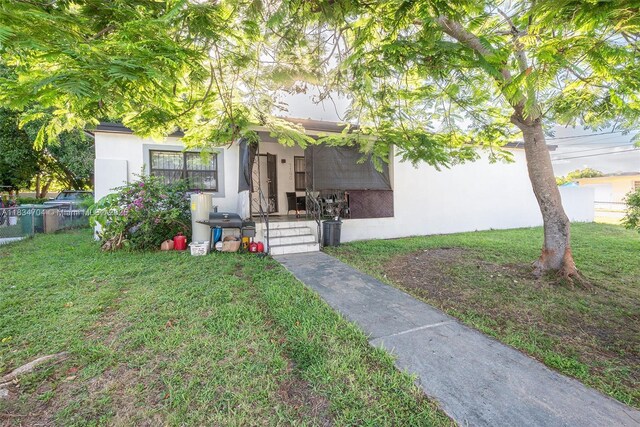 7190 NW 21st Ave, Miami, FL 33147 - view of property hidden behind natural elements featuring stucco siding, covered porch, and a front yard