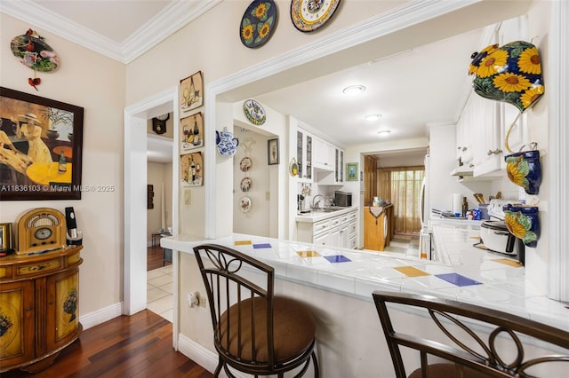 811 SW 25th Rd, Miami, FL 33129 - kitchen with a kitchen breakfast bar, dark wood-style flooring, white cabinets, tile countertops, and crown molding