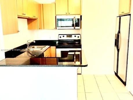 1865 Palm Cove Blvd Unit 9-306, Delray Beach, FL 33445 - kitchen featuring appliances with stainless steel finishes, a peninsula, tile patterned floors, and dark countertops
