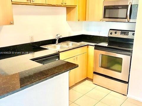 1865 Palm Cove Blvd Unit 9-306, Delray Beach, FL 33445 - kitchen featuring appliances with stainless steel finishes, light tile patterned floors, and dark stone counters