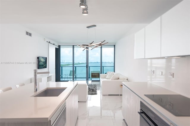 3131 NE 7th Ave Unit 1202, Miami, FL 33137 - kitchen featuring black electric cooktop, wall oven, floor to ceiling windows, white cabinetry, and modern cabinets