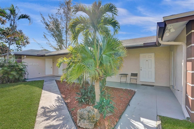 400 NE 2nd St, Boynton Beach, FL 33435 - view of exterior entry featuring stucco siding and a yard