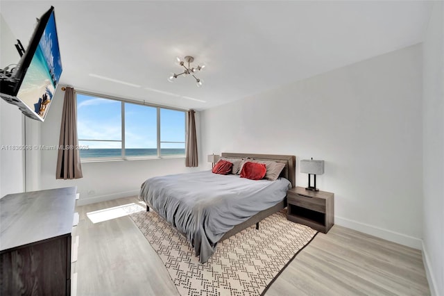 5005 Collins Ave Unit 815, Miami Beach, FL 33140 - bedroom with light wood finished floors, a water view, and a chandelier