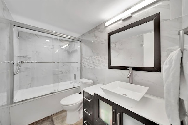 5005 Collins Ave Unit 815, Miami Beach, FL 33140 - full bathroom with tile walls, vanity, bath / shower combo with glass door, and wood finished floors