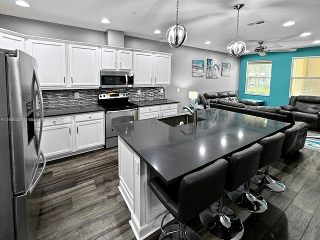 4126 Cascada Cir, Cooper City, FL 33024 - kitchen featuring stainless steel appliances, dark countertops, recessed lighting, open floor plan, and white cabinets