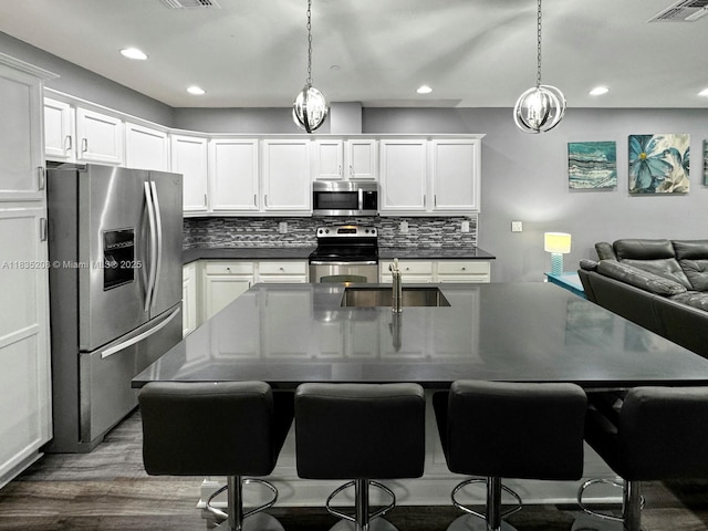 4126 Cascada Cir, Cooper City, FL 33024 - kitchen featuring appliances with stainless steel finishes, dark countertops, dark wood-style flooring, tasteful backsplash, and decorative light fixtures