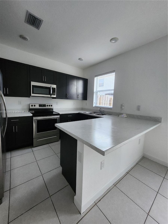 2693 SE 19th St, Homestead, FL 33035 - kitchen with stainless steel appliances, dark cabinets, a peninsula, light tile patterned floors, and recessed lighting