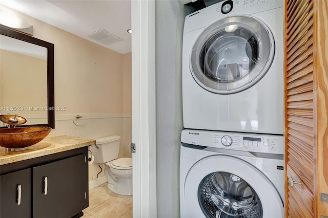 2921 SW 87th Ave Unit 511, Davie, FL 33328 - washroom with stacked washer / drying machine, light tile patterned flooring, and a wainscoted wall