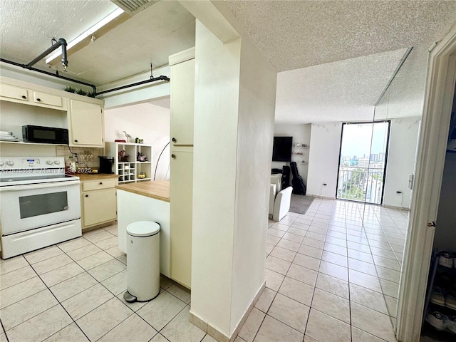 210 174th St Unit 1215, Sunny Isles Beach, FL 33160 - kitchen featuring electric stove, black microwave, a textured ceiling, light tile patterned floors, and open floor plan