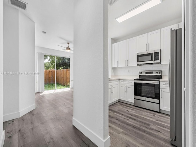 1456 SE 26th Ave, Homestead, FL 33035 - kitchen with appliances with stainless steel finishes, wood finished floors, white cabinets, a ceiling fan, and backsplash