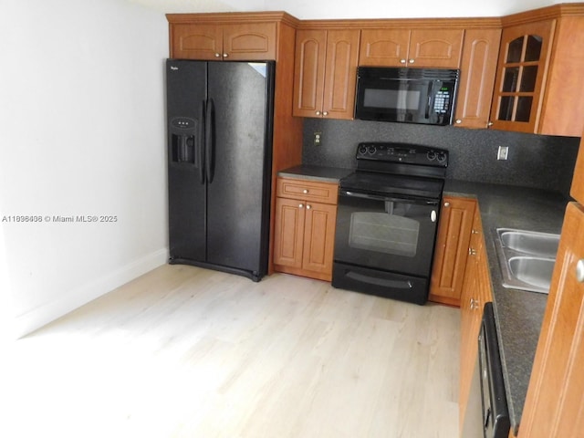 323 Ives Dairy Rd Unit 323-06, Miami, FL 33179 - kitchen featuring black appliances, dark countertops, light wood finished floors, glass insert cabinets, and brown cabinetry
