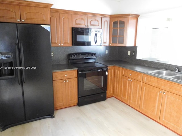 323 Ives Dairy Rd Unit 323-06, Miami, FL 33179 - kitchen featuring black appliances, light wood-type flooring, dark countertops, and glass insert cabinets