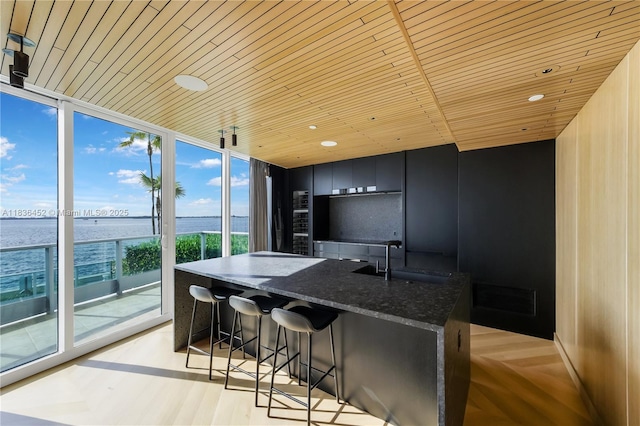 1331 Brickell Bay Dr Unit Bl-21, Miami, FL 33131 - kitchen featuring wood ceiling, a water view, a kitchen breakfast bar, a kitchen island with sink, and dark stone countertops