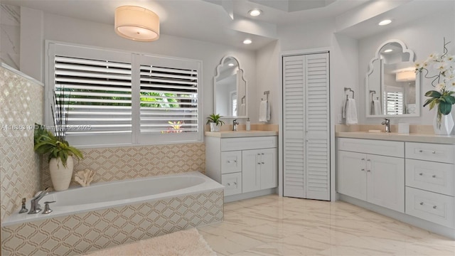 9099 NW 47th Ct, Coral Springs, FL 33067 - bathroom featuring a closet, two vanities, a bath, marble look tile flooring, and recessed lighting